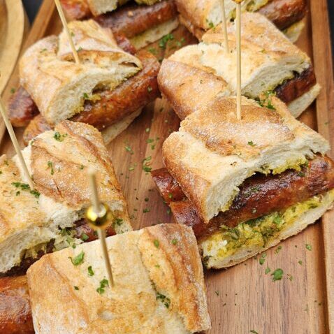 Classic Argentine Choripan (Chorizo Sandwich) served with fresh, house-made chimichurri sauce.