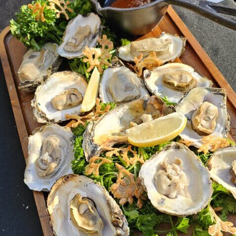 Fresh oysters roasting over embers, a signature luxury course for Fuegos Grill.