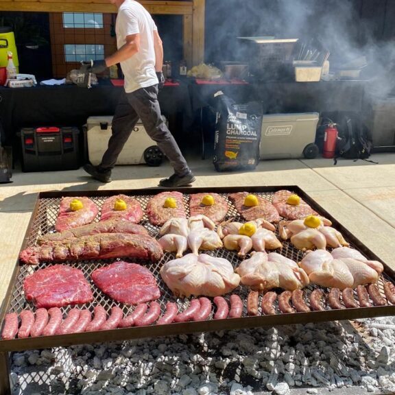 A massive live-fire grill loaded with premium cuts for a large-scale wedding or event.